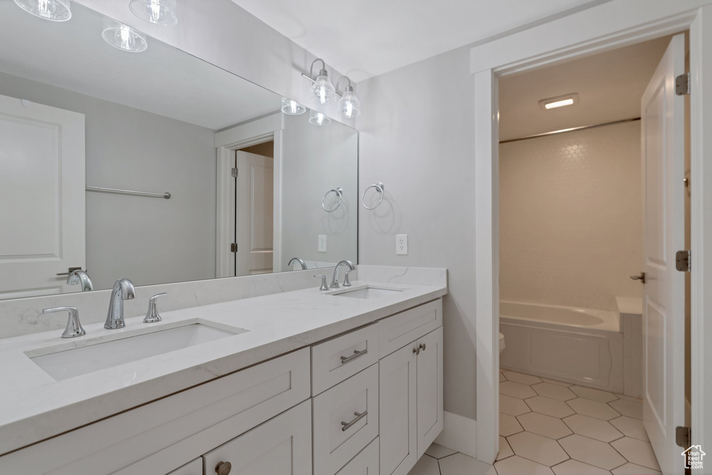 Bathroom with dual sinks, toilet, large vanity, and tile floors