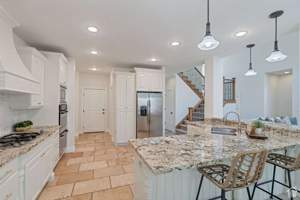 Kitchen featuring light tile floors, sink, white cabinetry, stainless steel appliances, and kitchen peninsula