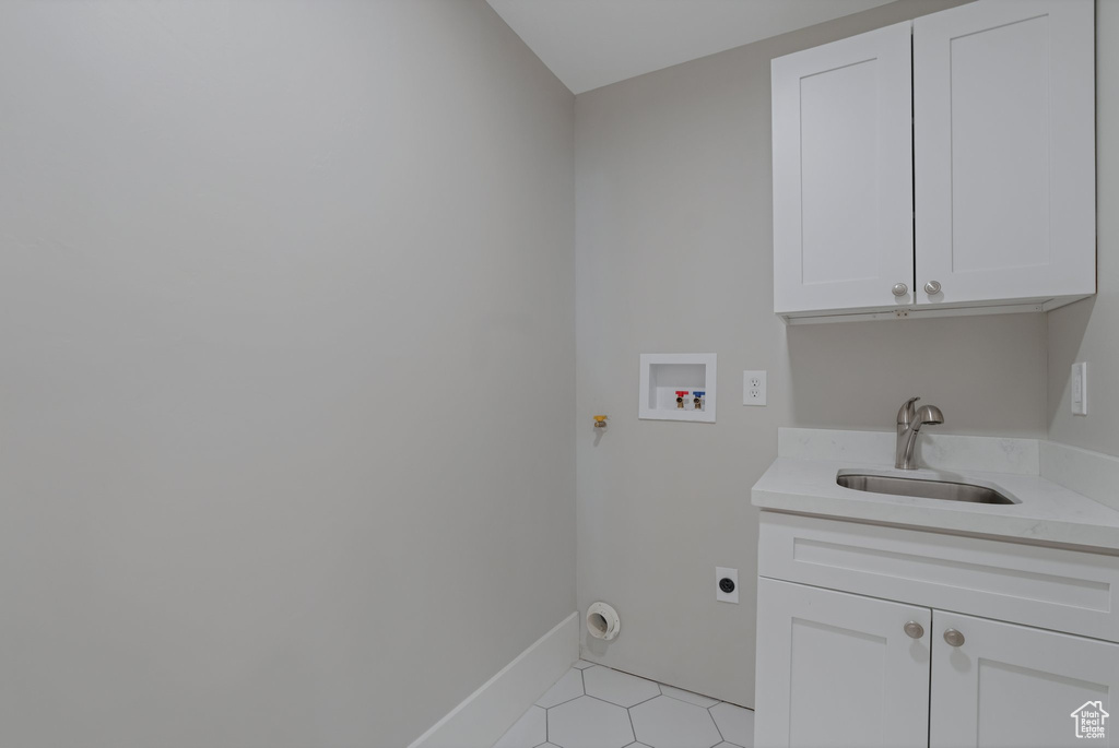 Washroom with hookup for an electric dryer, hookup for a washing machine, cabinets, light tile flooring, and sink