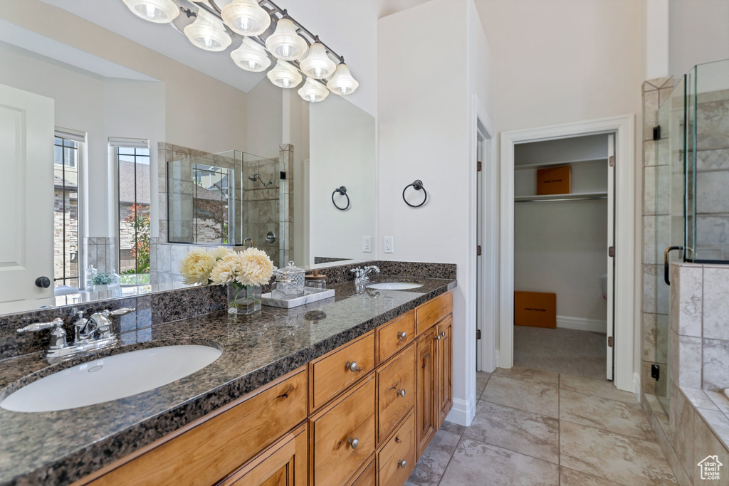 Bathroom featuring a shower with door, a chandelier, double sink, oversized vanity, and tile flooring