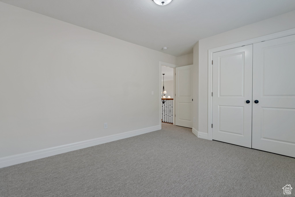 Unfurnished bedroom featuring a closet, a chandelier, and carpet floors