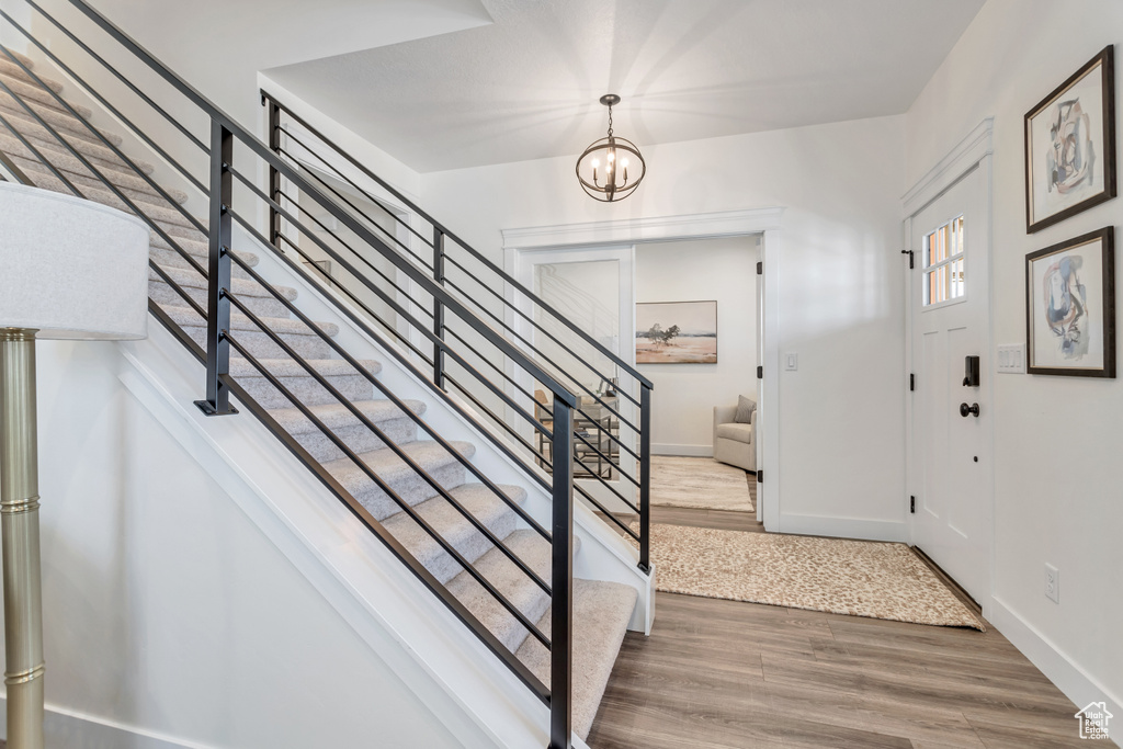 Stairway featuring an inviting chandelier and light wood-type flooring