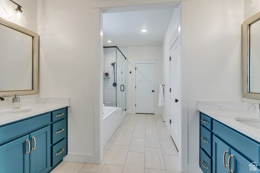 Bathroom featuring tile flooring, double sink vanity, and a shower with door