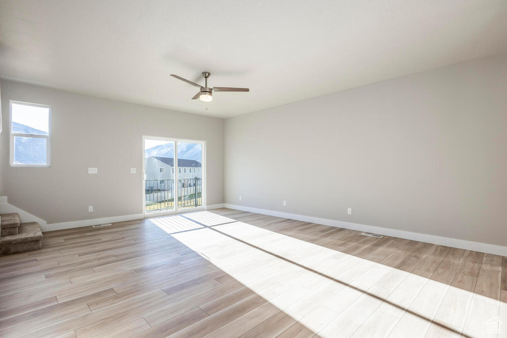 Empty room with ceiling fan and light hardwood / wood-style flooring