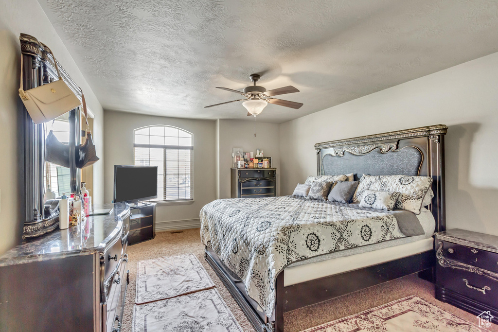 Bedroom featuring ceiling fan, light colored carpet, and a textured ceiling