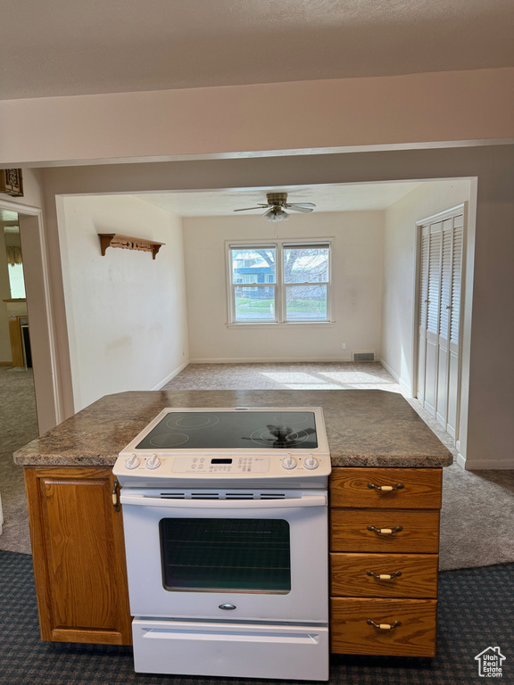 Kitchen with ceiling fan, dark colored carpet, and white range oven