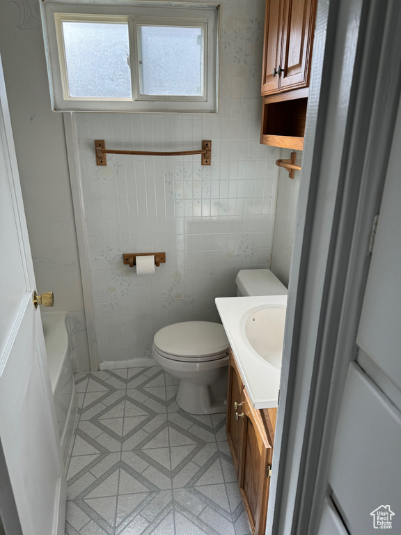 Bathroom featuring toilet, tile flooring, vanity, and tile walls