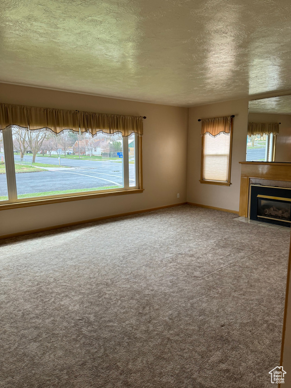 Unfurnished living room with carpet and a textured ceiling