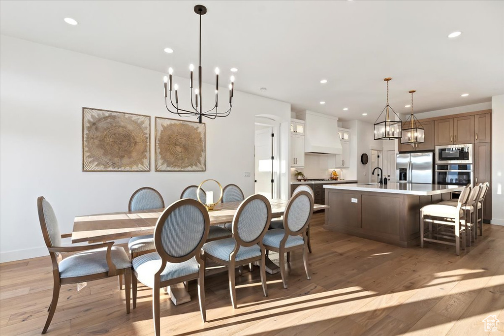Dining space with sink, light hardwood / wood-style floors, and an inviting chandelier