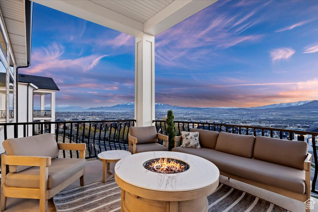 Balcony at dusk featuring an outdoor living space with a fire pit and a mountain view