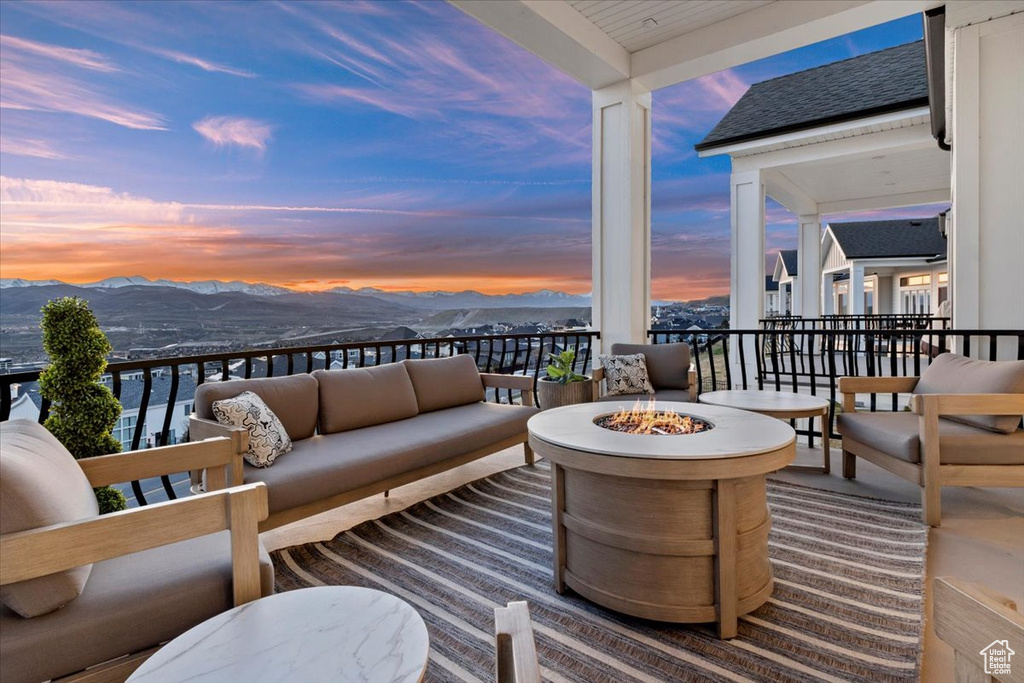 Balcony at dusk with an outdoor living space with a fire pit and a mountain view