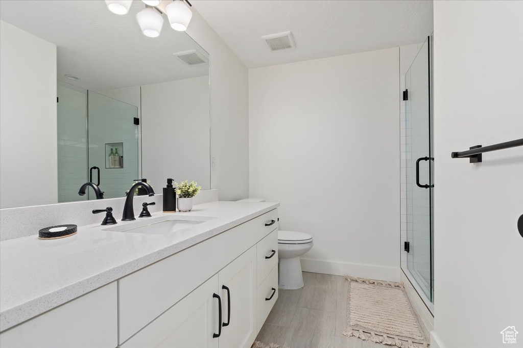 Bathroom featuring toilet, a shower with shower door, and large vanity