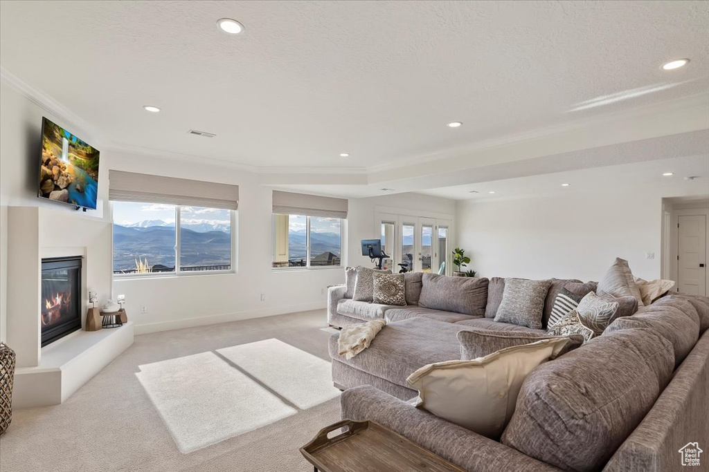 Living room featuring a mountain view, french doors, light colored carpet, and a healthy amount of sunlight