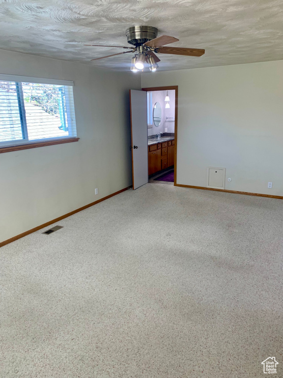 Empty room featuring ceiling fan, a textured ceiling, and carpet