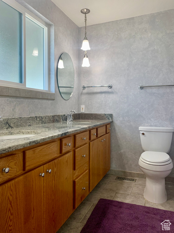 Bathroom featuring toilet, double sink vanity, and tile flooring