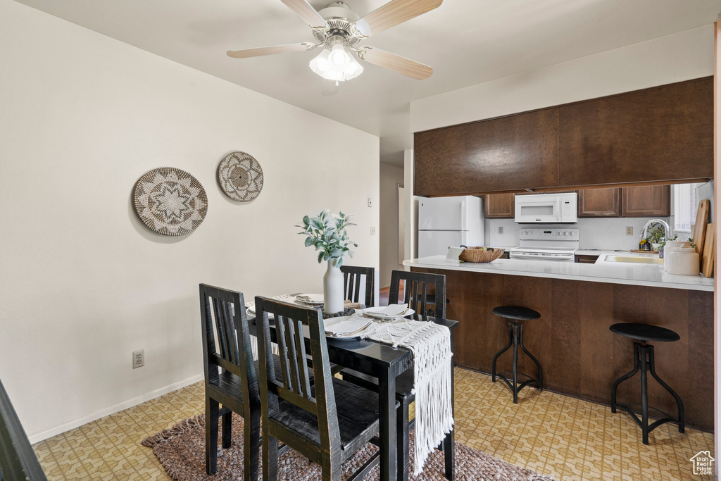 Tiled dining room with ceiling fan and sink