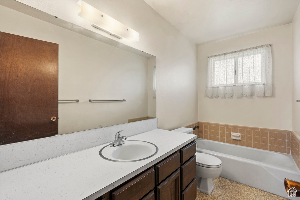 Bathroom with a bathtub, toilet, and vanity with extensive cabinet space