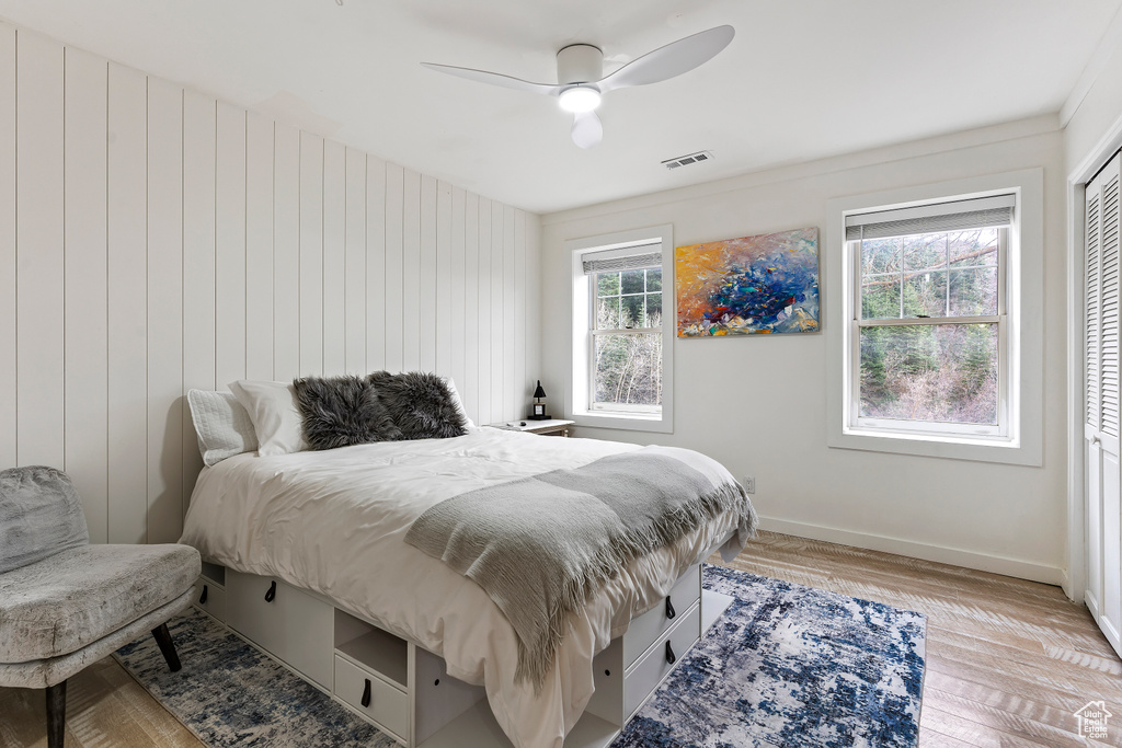 Bedroom featuring ceiling fan, a closet, light hardwood / wood-style floors, and multiple windows