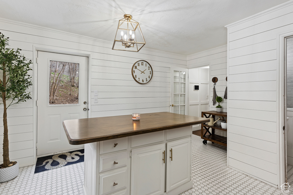 Kitchen with wooden walls, white cabinetry, and decorative light fixtures