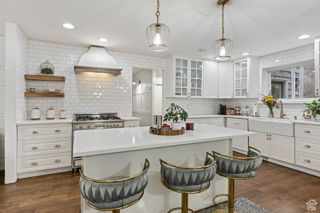 Kitchen featuring white cabinets, sink, dark hardwood / wood-style flooring, pendant lighting, and tasteful backsplash