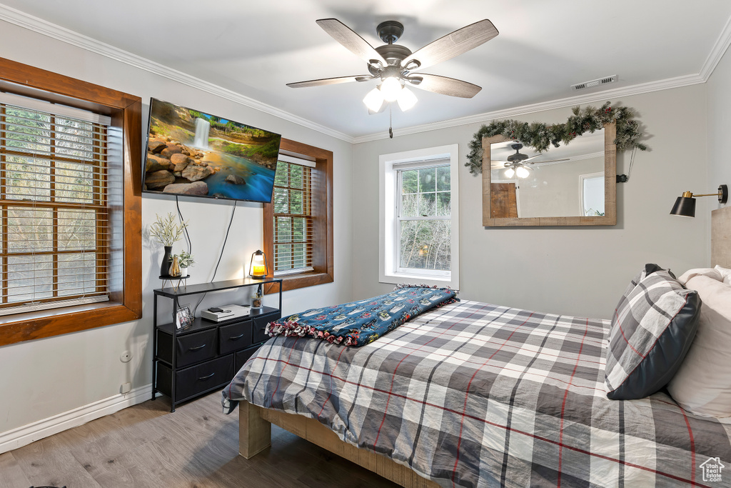 Bedroom with ceiling fan, ornamental molding, and hardwood / wood-style flooring