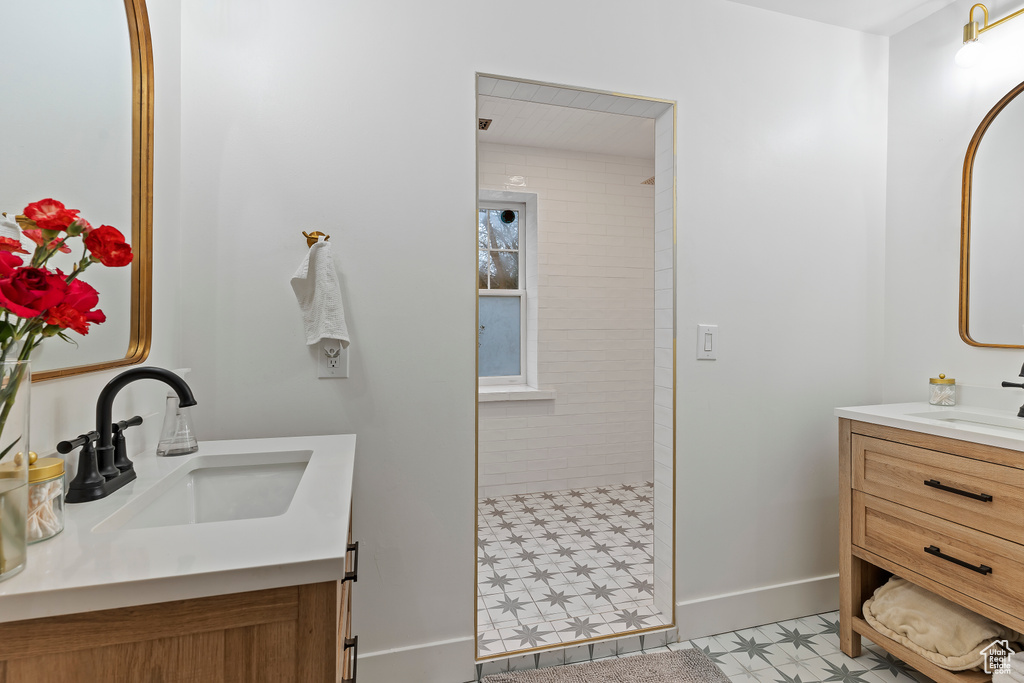 Bathroom featuring tile flooring, double sink vanity, and tiled shower