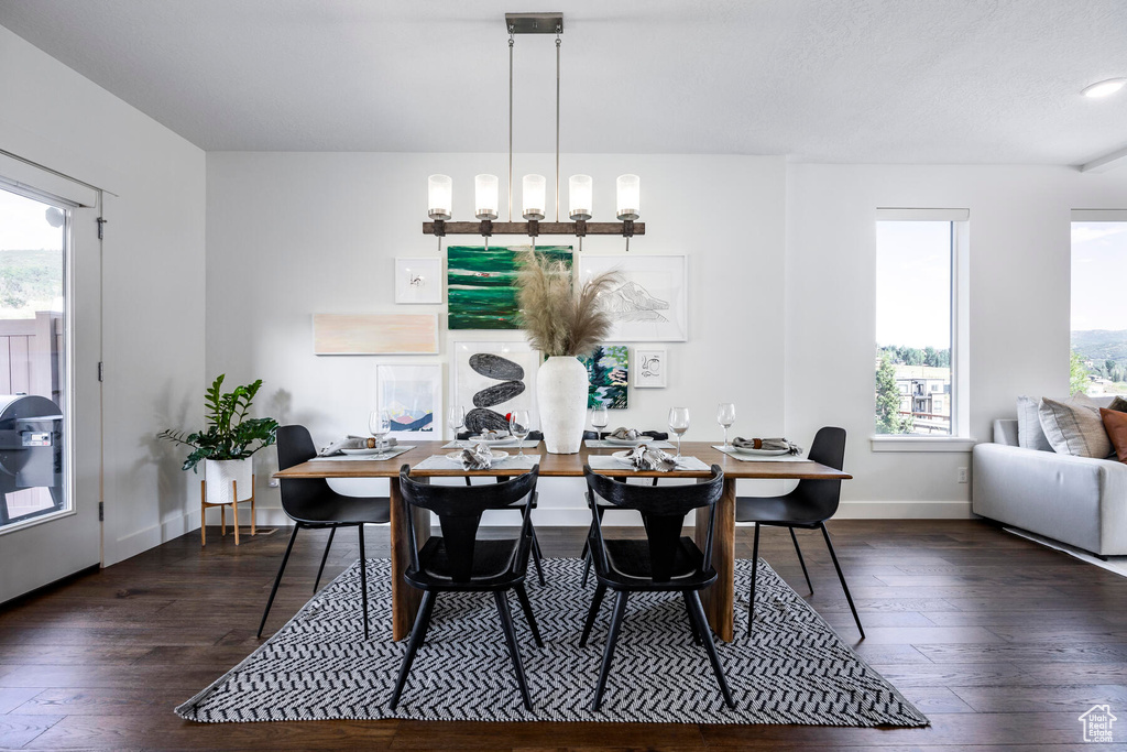Dining space featuring dark wood-type flooring, a wealth of natural light, and a chandelier
