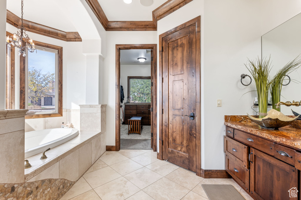 Bathroom featuring crown molding, a relaxing tiled bath, a chandelier, tile floors, and vanity