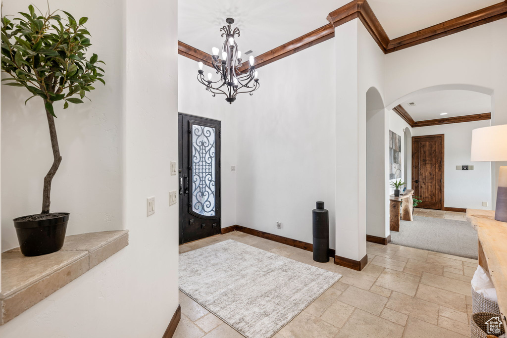 Entrance foyer with a notable chandelier, crown molding, and light tile floors