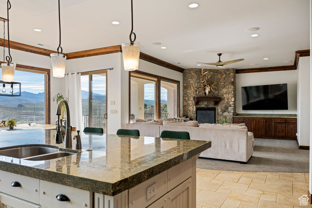 Kitchen with sink, ceiling fan, a fireplace, a mountain view, and decorative light fixtures