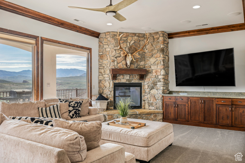 Carpeted living room featuring ceiling fan, a healthy amount of sunlight, a fireplace, and a mountain view