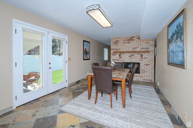 Dining area with light tile flooring, brick wall, a brick fireplace, and french doors