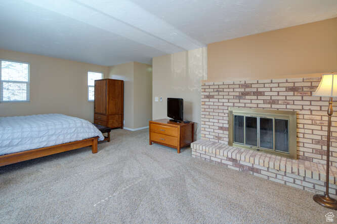 Bedroom with light carpet and a brick fireplace