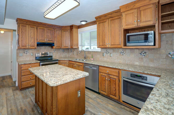 Kitchen featuring appliances with stainless steel finishes, tasteful backsplash, and light stone countertops