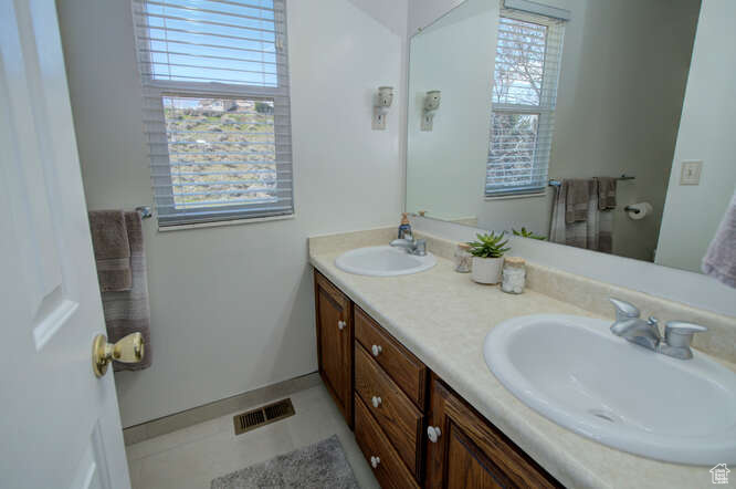 Bathroom featuring dual vanity, tile flooring, and a wealth of natural light