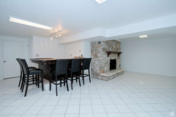 Tiled dining area featuring a stone fireplace and indoor bar