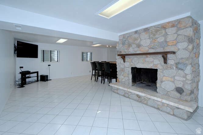 Tiled living room featuring a stone fireplace