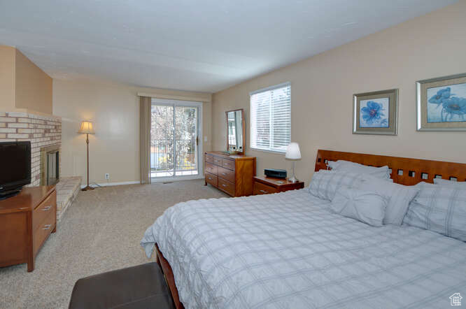 Bedroom with a brick fireplace and light colored carpet
