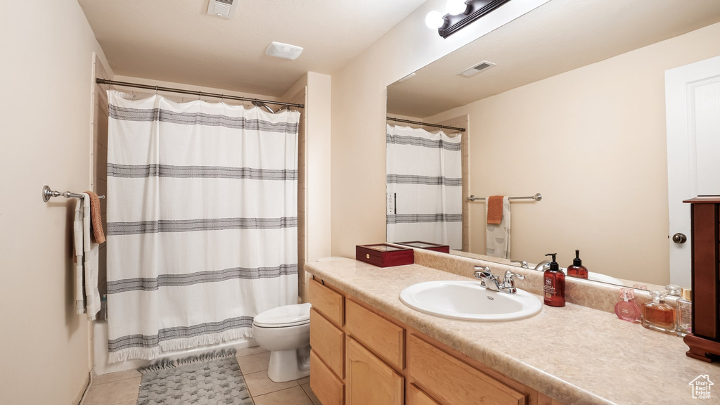 Bathroom featuring tile flooring, toilet, and vanity with extensive cabinet space