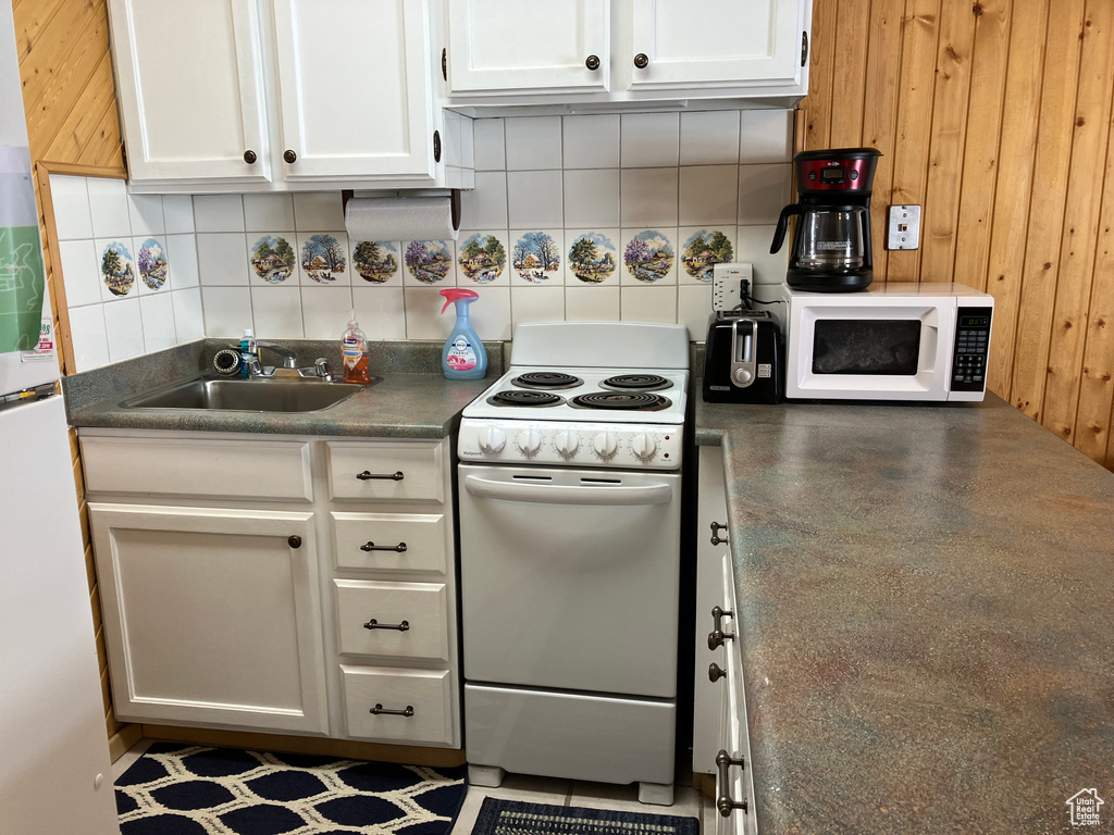 Kitchen featuring white cabinets, backsplash, white appliances, and sink