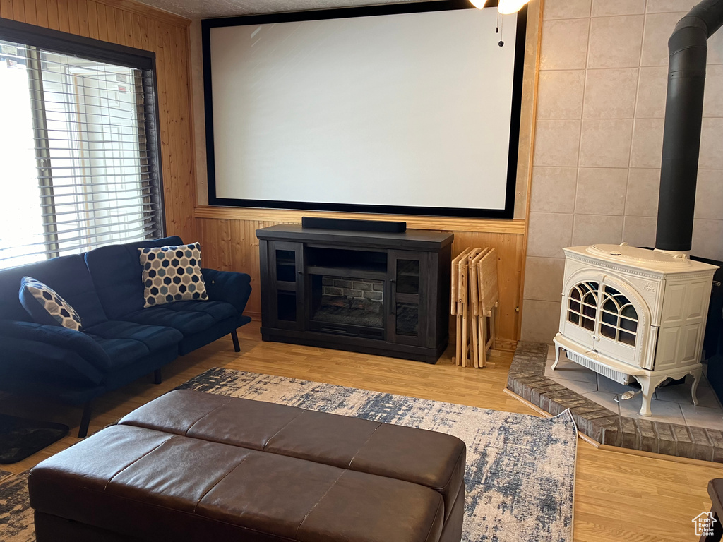 Home theater room with a wood stove, wood-type flooring, plenty of natural light, and tile walls