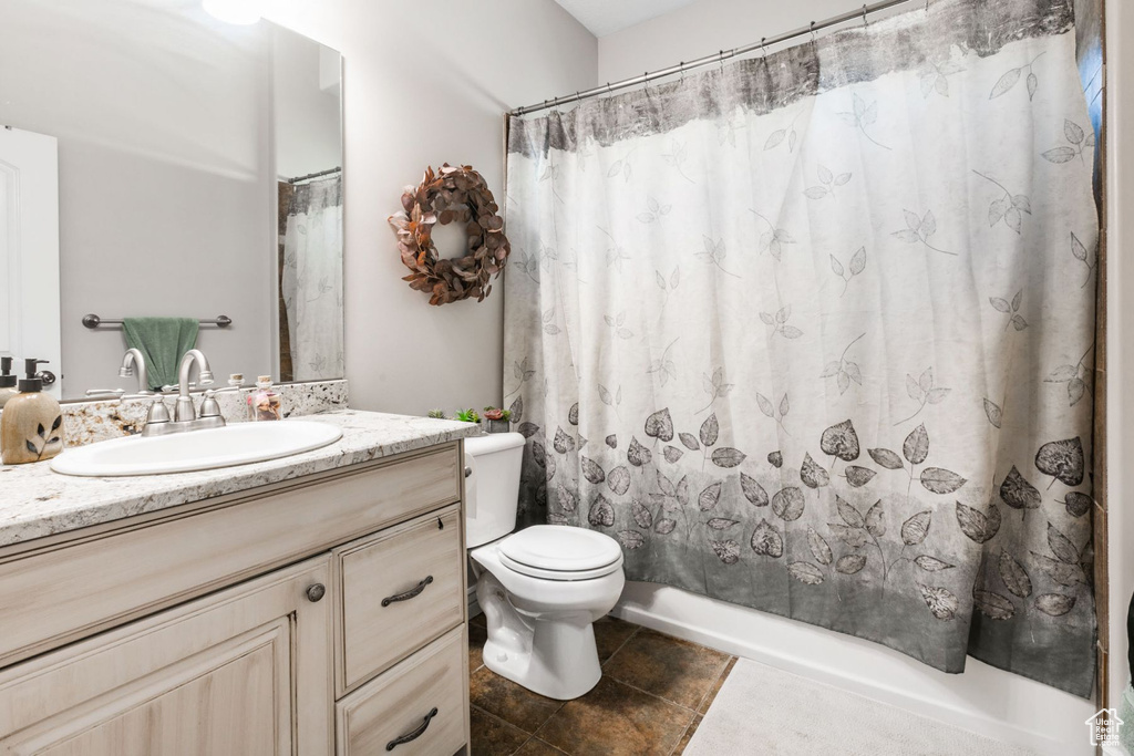 Full bathroom with tile floors, toilet, shower / tub combo, and vanity