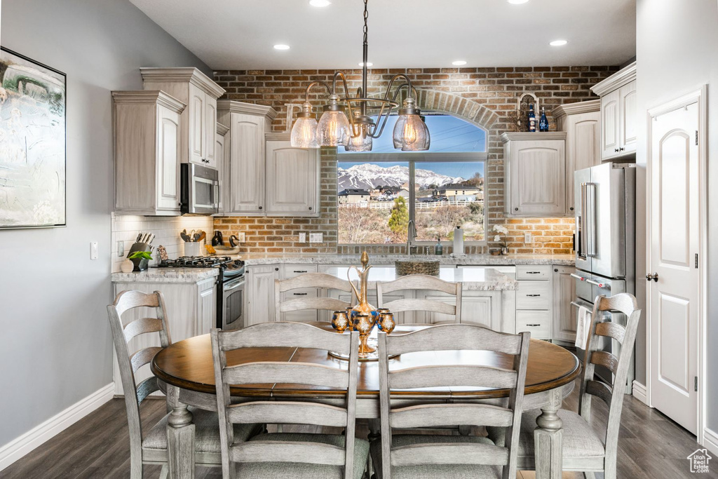 Kitchen featuring pendant lighting, a notable chandelier, appliances with stainless steel finishes, dark hardwood / wood-style floors, and light stone counters