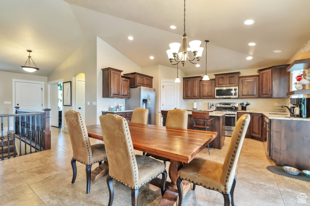 Dining space featuring an inviting chandelier, lofted ceiling, sink, and light tile flooring