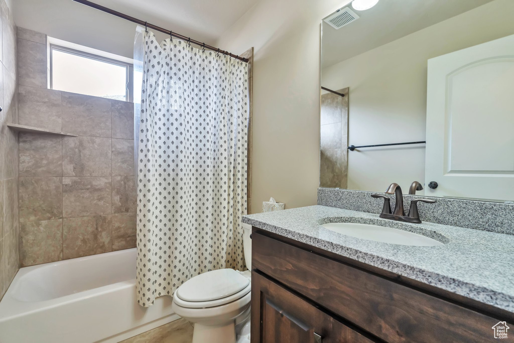 Full bathroom featuring shower / tub combo with curtain, toilet, and vanity