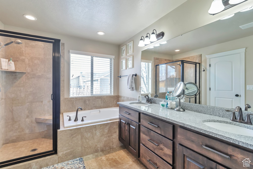 Bathroom featuring tile flooring, a textured ceiling, dual bowl vanity, and independent shower and bath
