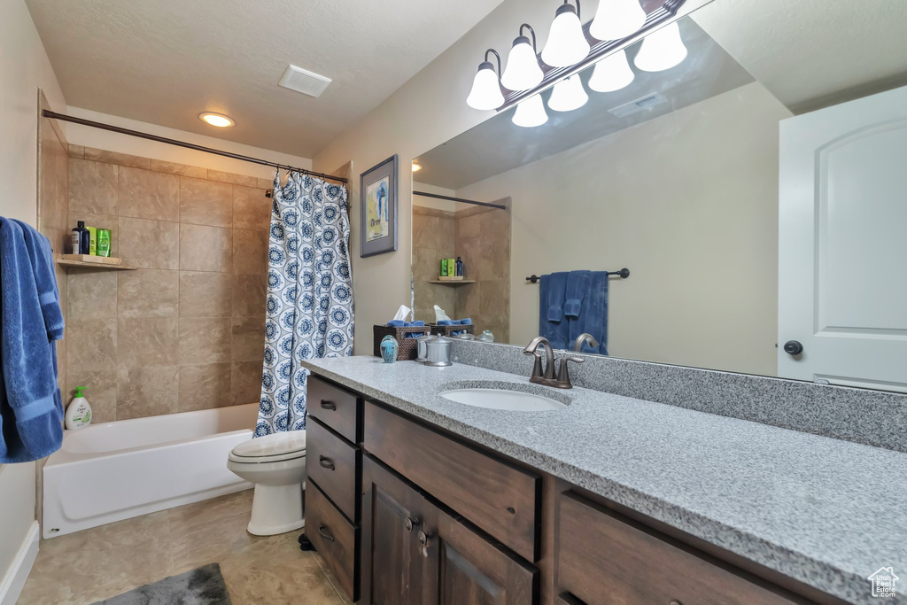 Full bathroom with shower / bath combination with curtain, toilet, tile floors, and vanity with extensive cabinet space