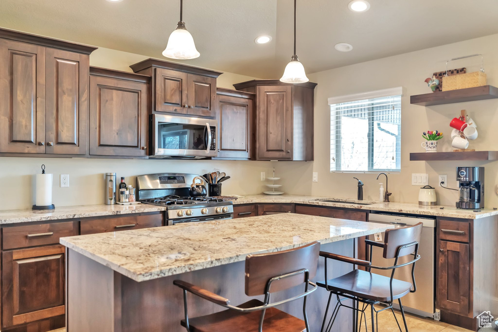 Kitchen with sink, hanging light fixtures, stainless steel appliances, and a kitchen breakfast bar