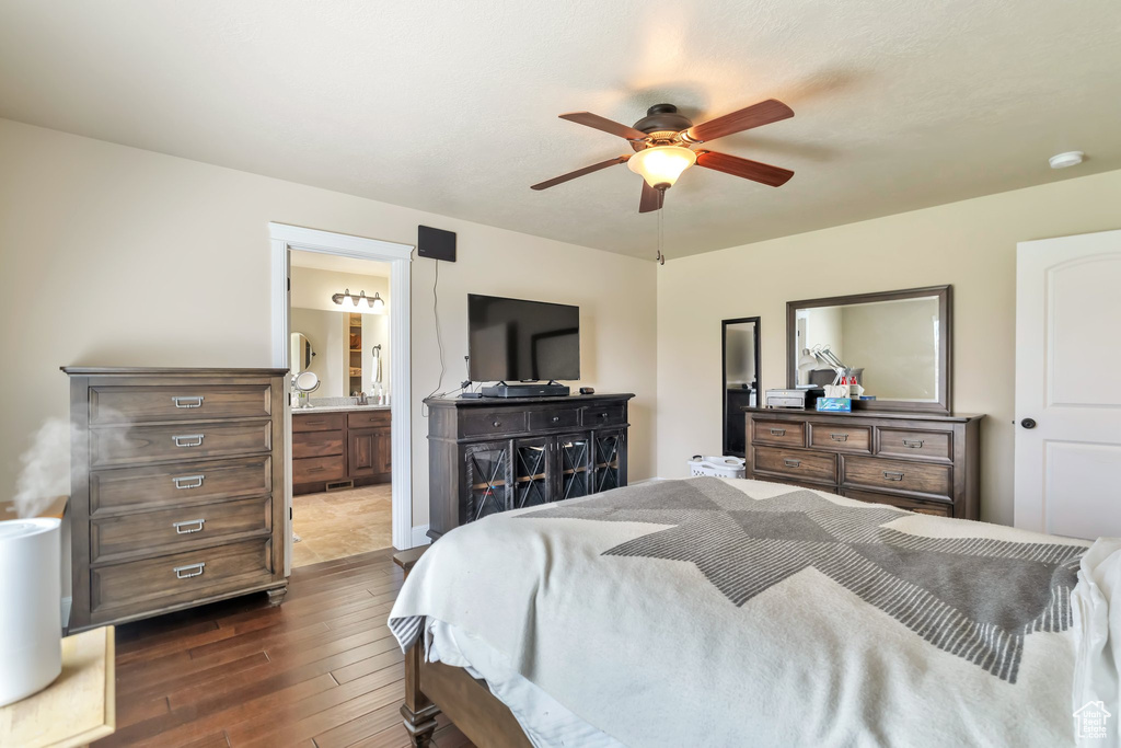 Bedroom with dark tile floors, ceiling fan, and connected bathroom