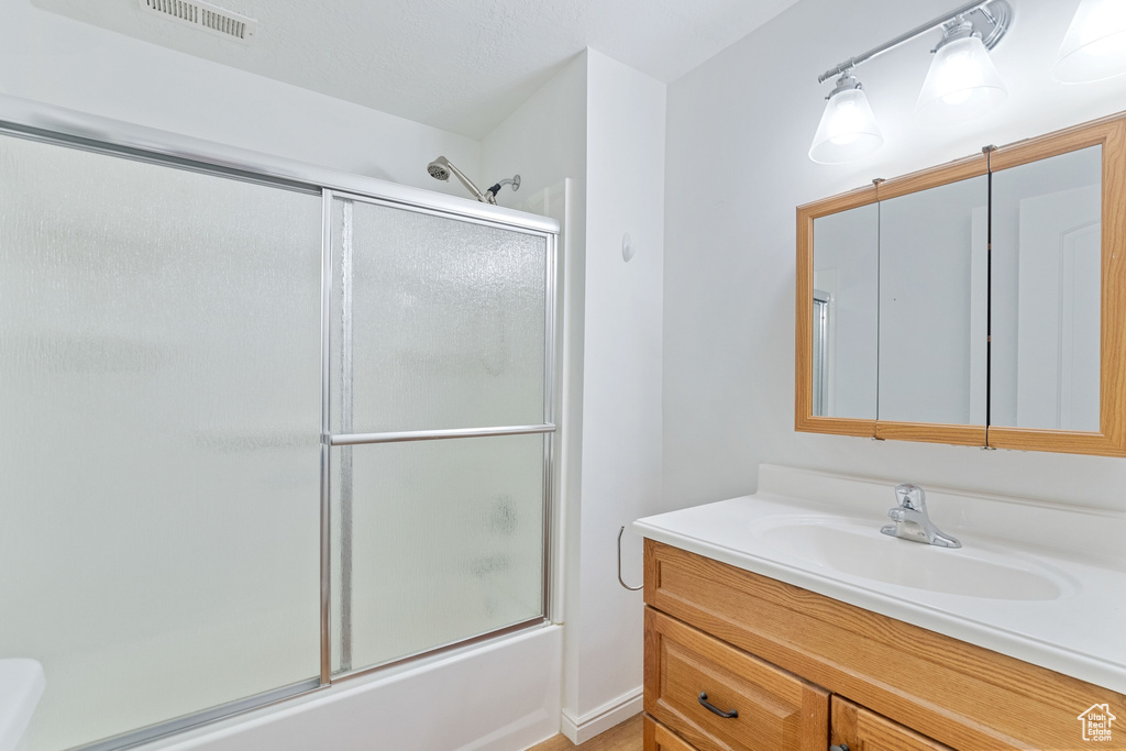 Full bathroom with toilet, shower / bath combination with glass door, and vanity